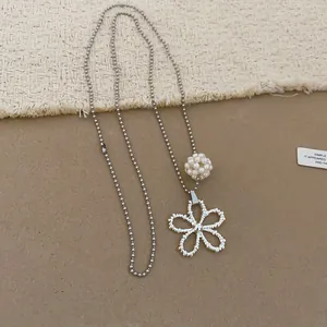 Close-up of silver beaded necklace with hollow flower pendant and pearl ball detail