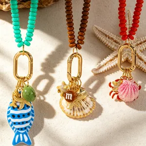Primer plano de collares de cuentas con tema oceánico y dijes de concha, pez y cangrejo