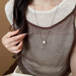 Detailed view of silver flower pendant necklace with white pearl on model's chest