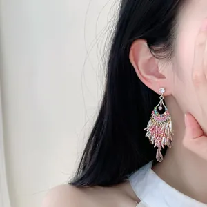 Chandelier dangle earrings featuring colorful beads and glass tassels worn by an Asian model