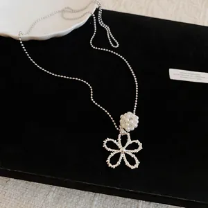 Detail of silver flower and pearl ball pendant on a minimalist ball chain necklace