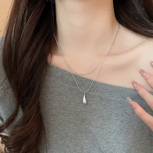 Close-up of minimalist double-layered silver necklace with a sleek waterdrop pendant.