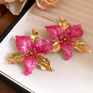 Close-up of vintage gold-plated floral earrings with vibrant pink enamel petals
