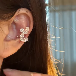 Primo piano dettagliato di un elegante ear cuff a doppio cuore in zircone su modella