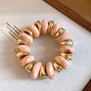 Detailed view of marbled pink beads and gold spacers on a vintage style bracelet