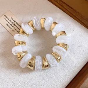 Macro view of white marbled resin beads and gold spacers on a vintage bracelet