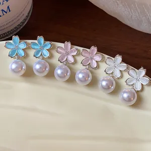 Detailed macro view of elegant flower pearl drop earrings in blue, pink, and white colors.