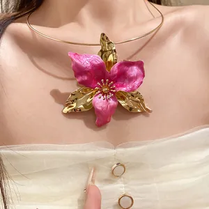 Detail view of an elegant vintage pink enamel flower pendant on a gold choker necklace.