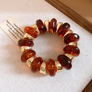Detailed view of a retro amber resin bracelet with golden spacers on rustic wood