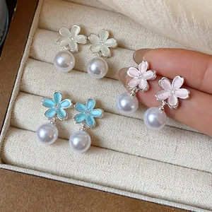 Elegant flower stud earrings with pearls in three colors, close-up jewelry detail view.