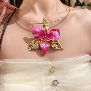 Detailed view of a vintage pink enamel flower pendant on an elegant gold torque choker