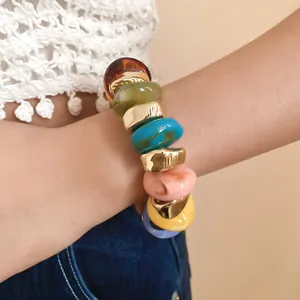 Close-up of a colorful chunky round beaded bracelet with gold-toned metallic accents on a wrist.