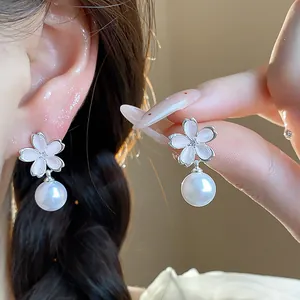 Close-up of elegant silver zircon flower earrings with white pearl drop for women.