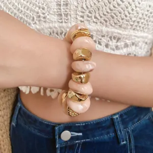 Detailed view of an elegant marbled resin and gold-tone irregular bead bracelet worn on wrist