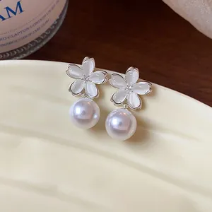 Macro detail of elegant French style cherry blossom and white pearl drop earrings