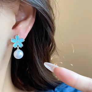 Detailed close-up showing elegant blue flower earring with pearl drop on ear lobe