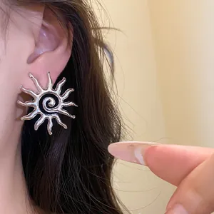 Primo piano di orecchino a forma di sole argentato con spirale, indossato.
