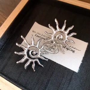 Primo piano di orecchini a sole in argento con design a spirale in un portagioie