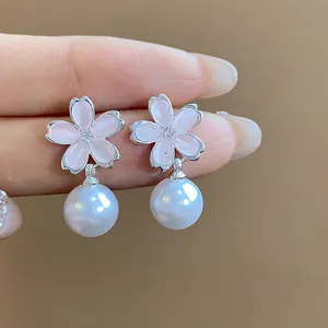 Close-up of elegant cherry blossom earrings with pink petals and white pearl drops.