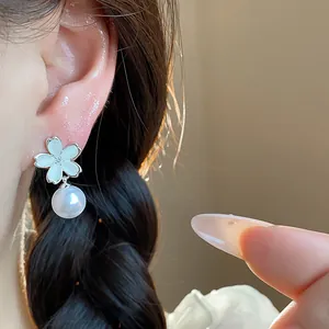 Close-up detail of elegant white flower pearl stud earrings worn on ear with soft lighting