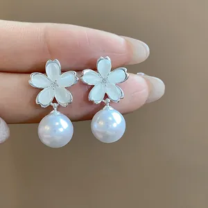 Macro detail of elegant silver flower earrings featuring white pearls and zircon