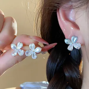Gros plan sur les boucles d'oreilles fleur en zircon et finition goutte d'huile
