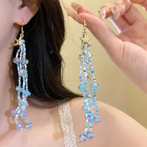 Detailed close-up of long starfish beaded tassel earrings with blue and white accents