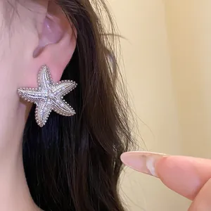 Primo piano di un elegante orecchino a stella marina argentato con inserti di perle all'orecchio