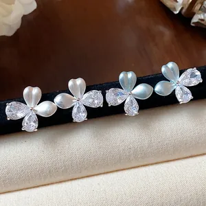 Gros plan détaillé de boucles d'oreilles fleurs en argent avec zircons étincelants.