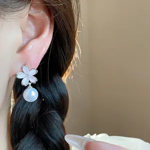 Macro view of elegant silver zircon flower stud earrings with a delicate white pearl.