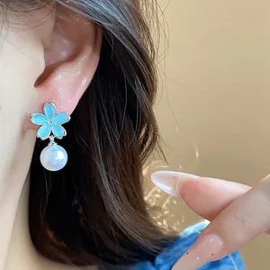 Close-up of blue flower pearl earring worn on ear, French minimalist style jewelry