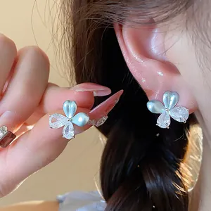Vue détaillée de boucles d'oreilles fleurs élégantes avec zircon et finition émail perlé.
