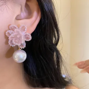 Dettaglio di un elegante orecchino a fiore di perline rosa con una grande perla cangiante
