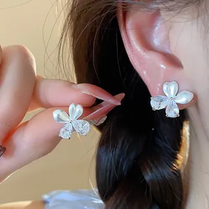 Détail en gros plan d'élégantes boucles d'oreilles fleurs en perles et zircons blancs