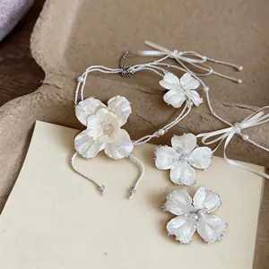 Dettaglio ravvicinato di un set di gioielli con fiori in tessuto, perle e perline