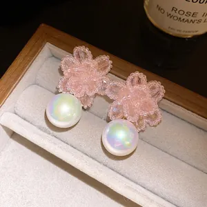 Dettaglio di orecchini a fiore in cristallo rosa con perle iridescenti
