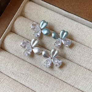 Détail de boucles d'oreilles fleurs avec zircons et pétales en émail bleu clair
