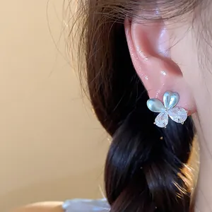 Gros plan détaillé d'une élégante boucle d'oreille fleur avec zircone et émail bleu clair chic
