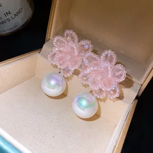 Dettaglio macro di orecchini a fiore con perline rosa e perle iridescenti