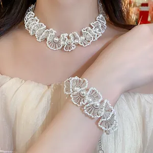 Close-up showing the elegant hand-beaded lace pearl necklace and bracelet set on a model