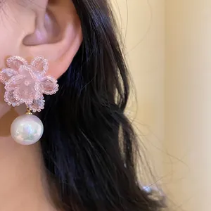 Macro di orecchino a fiore rosa con perline e una grande perla cangiante