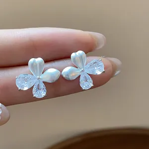 Vue détaillée de boucles d'oreilles fleurs en émail blanc et zircons clairs brillants