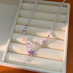 Elegant purple beaded necklace with a sparkling zircon flower pendant on a jewelry tray