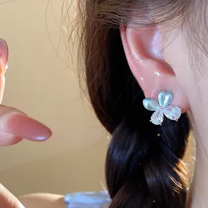 Gros plan d'une boucle d'oreille fleur délicate avec pétales bleus et zircons brillants
