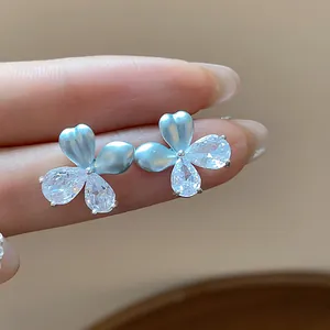 Détail macro de boucles d'oreilles fleur élégantes avec émail bleu clair et zircons brillants