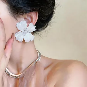 Elegante primo piano di un orecchino a fiore con perline di vetro bianche su una modella