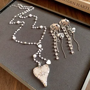 Detail view of a vintage-style pearl heart necklace and matching tassel earrings on a tray.