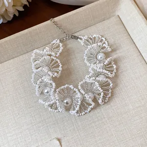 Elegant handmade white floral lace beaded necklace featuring pearls close-up view.