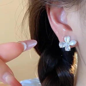 Détail macro d'une boucle d'oreille fleur en zircon avec des pétales nacrés élégants.