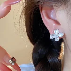 Détail en gros plan de boucles d'oreilles fleur en argent avec zircons et émail